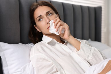 Photo of Sick woman with tissue in bed. Cold symptoms