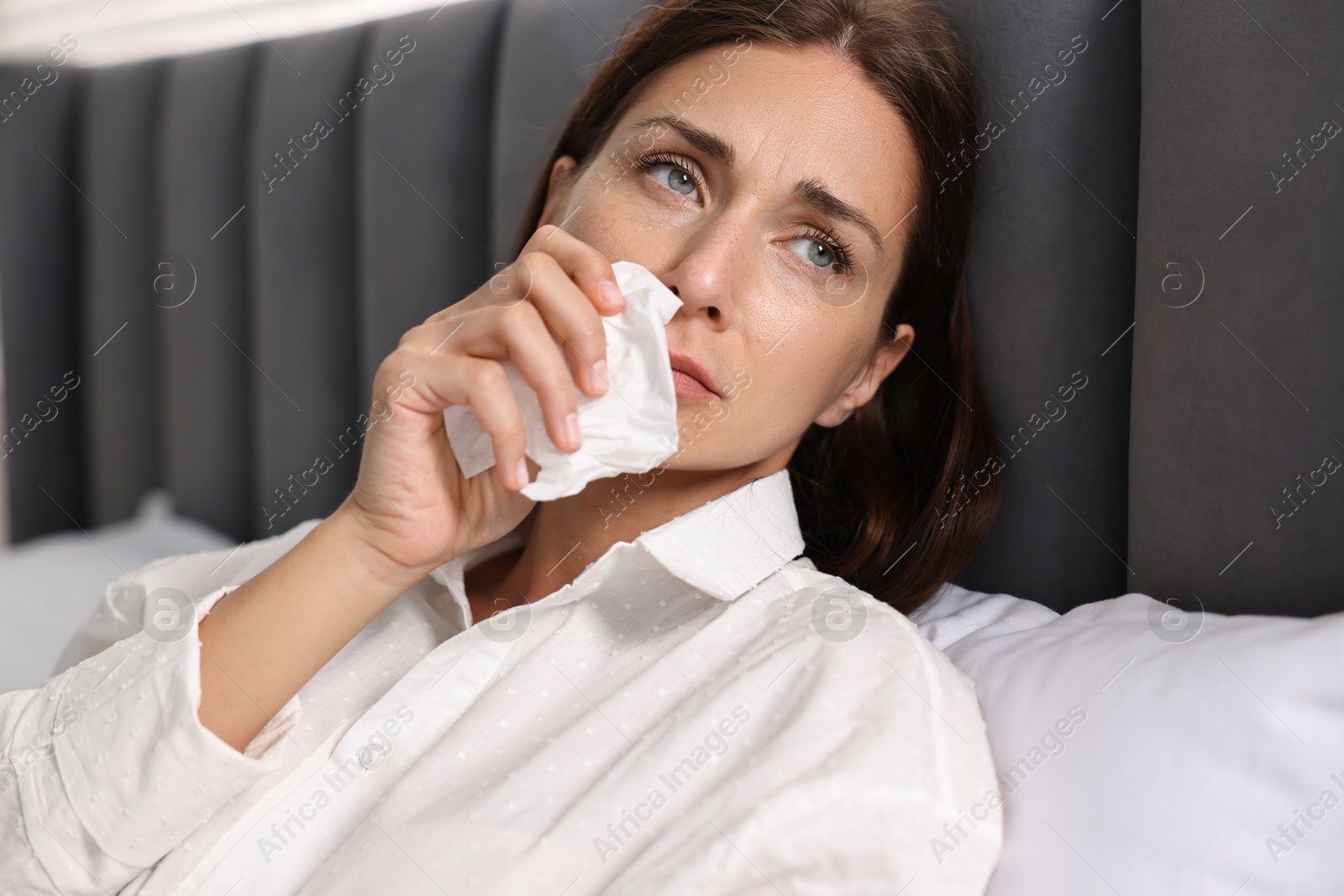 Photo of Sick woman with tissue in bed. Cold symptoms