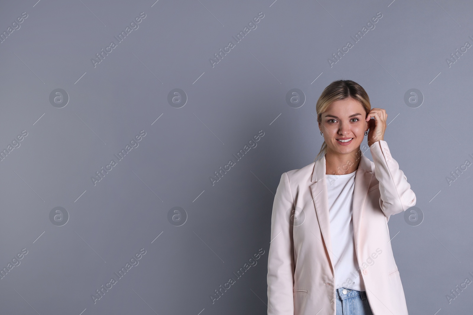 Photo of Beautiful woman in stylish jacket on grey background, space for text