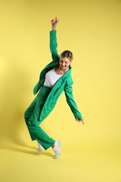 Photo of Beautiful woman in stylish green suit posing on yellow background