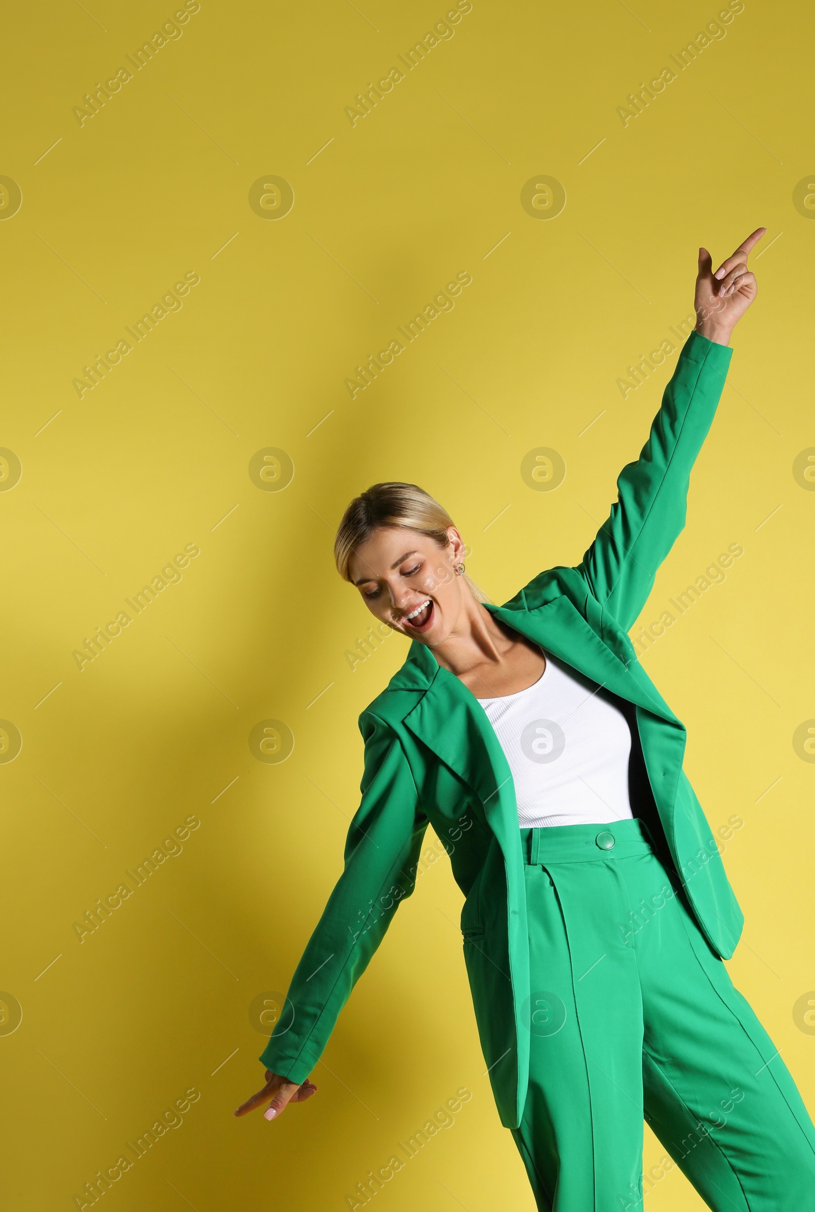 Photo of Beautiful woman in stylish green suit posing on yellow background