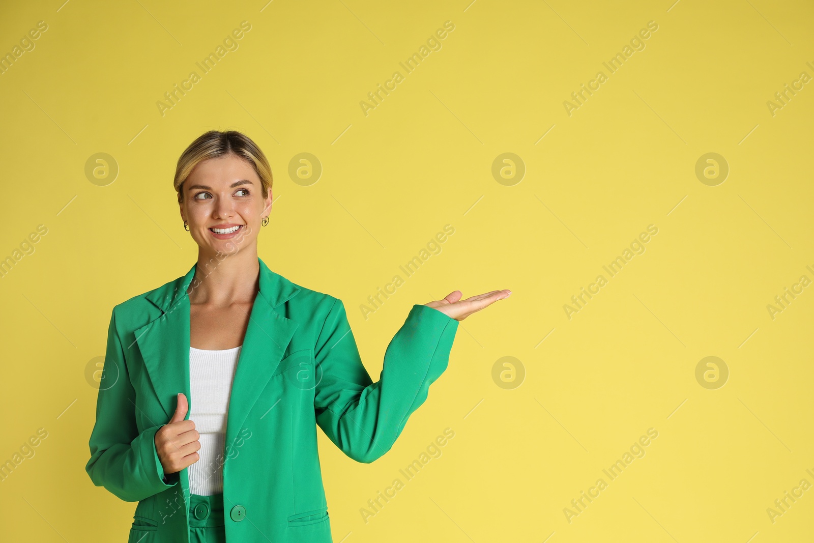 Photo of Beautiful woman in stylish green suit on yellow background, space for text