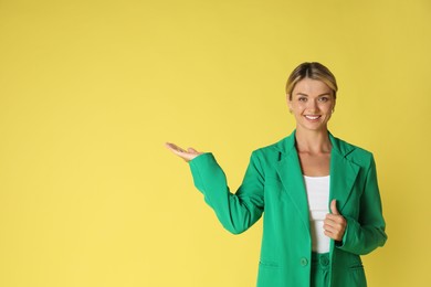 Photo of Beautiful woman in stylish green suit on yellow background, space for text