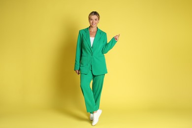 Photo of Beautiful woman in stylish green suit on yellow background