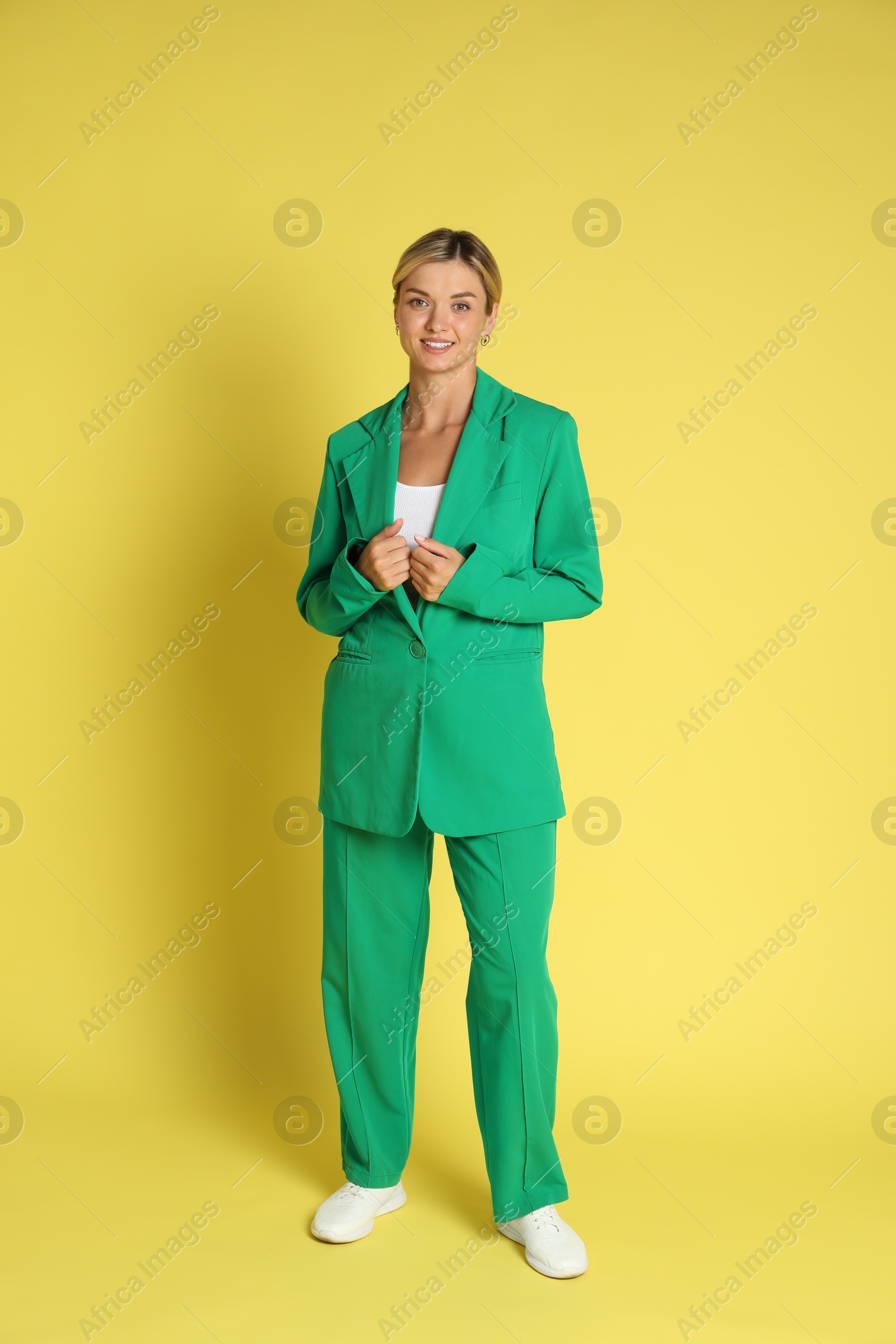 Photo of Beautiful woman in stylish green suit on yellow background