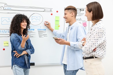 Photo of Developing UI design. People drawing website wireframe on whiteboard indoors