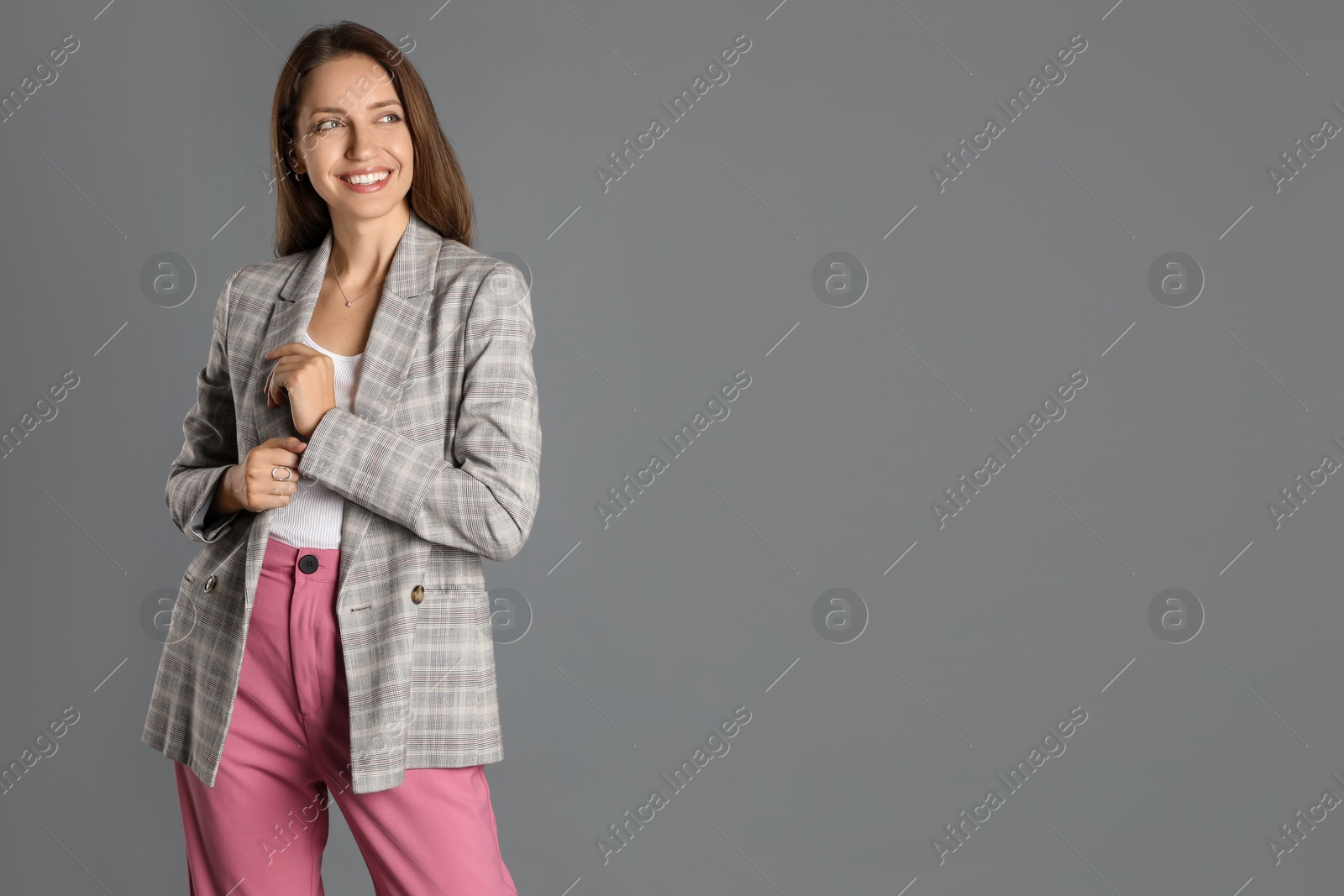 Photo of Beautiful woman in stylish jacket and pink pants on grey background. Space for text