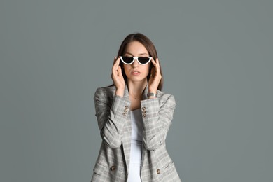 Photo of Beautiful woman with stylish jacket and sunglasses on grey background