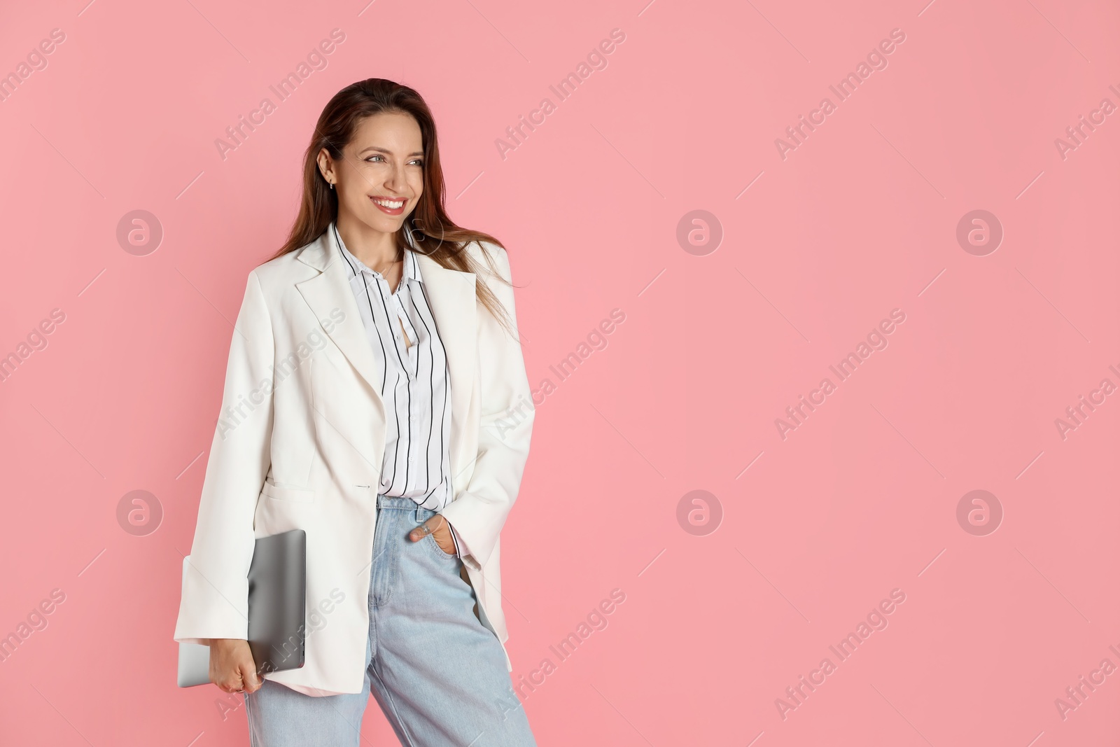 Photo of Beautiful woman in stylish white jacket with laptop on pink background, space for text