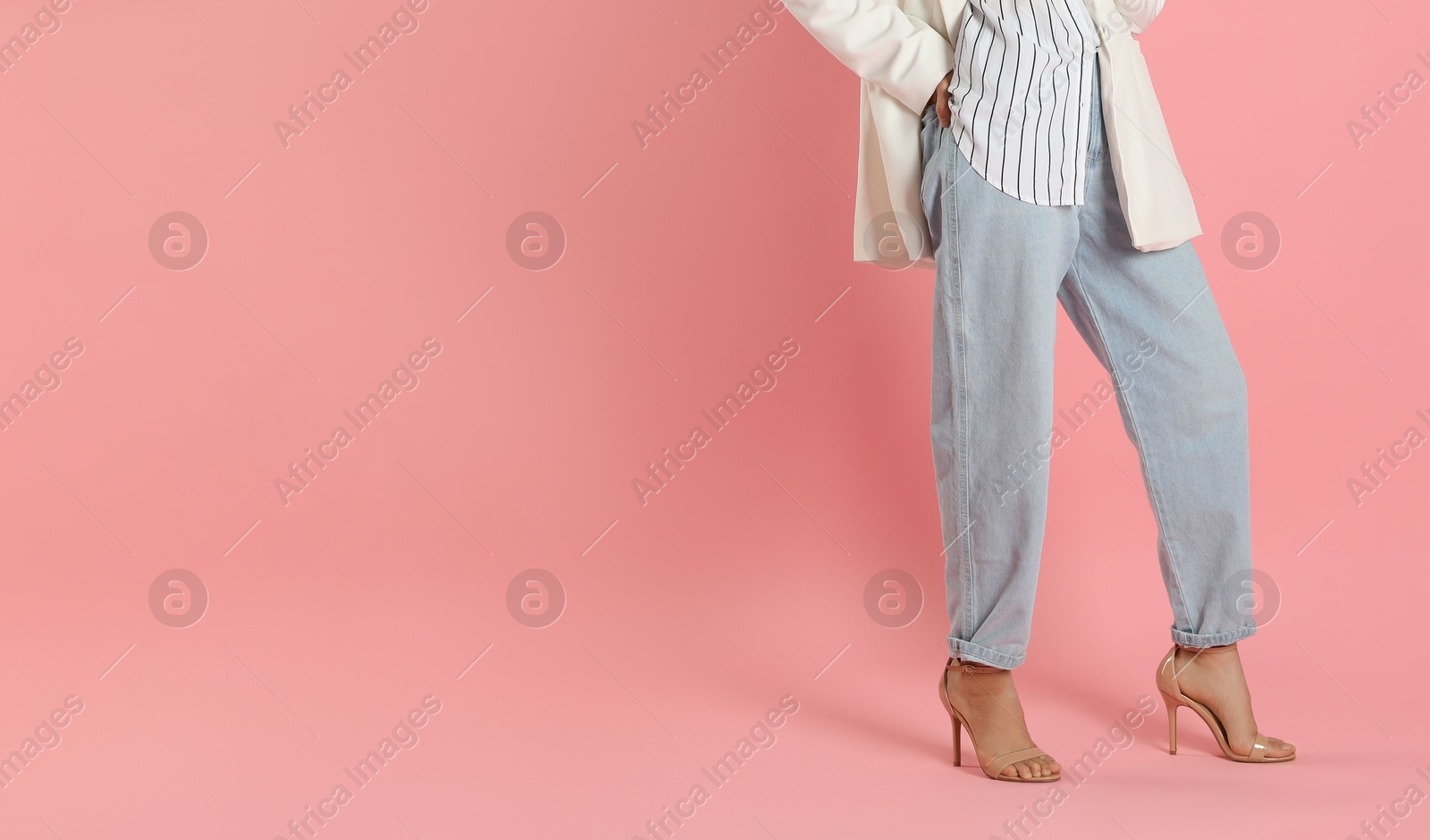 Photo of Beautiful woman in stylish white jacket and grey pants on pink background, closeup. Space for text