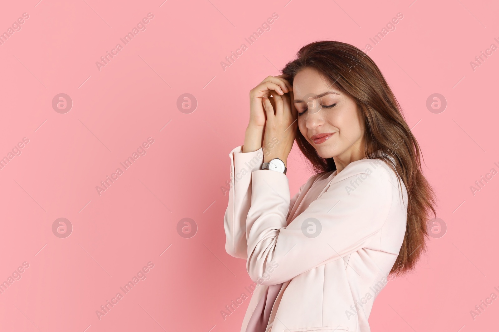 Photo of Beautiful woman in stylish white suit and watch on pink background, space for text