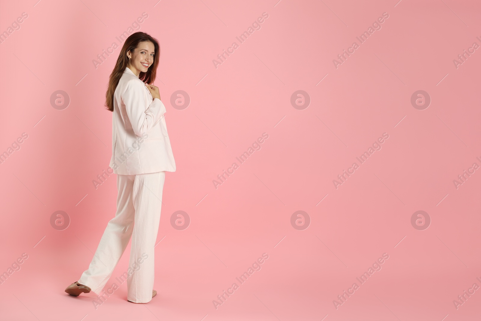 Photo of Beautiful woman in stylish white suit on pink background, space for text