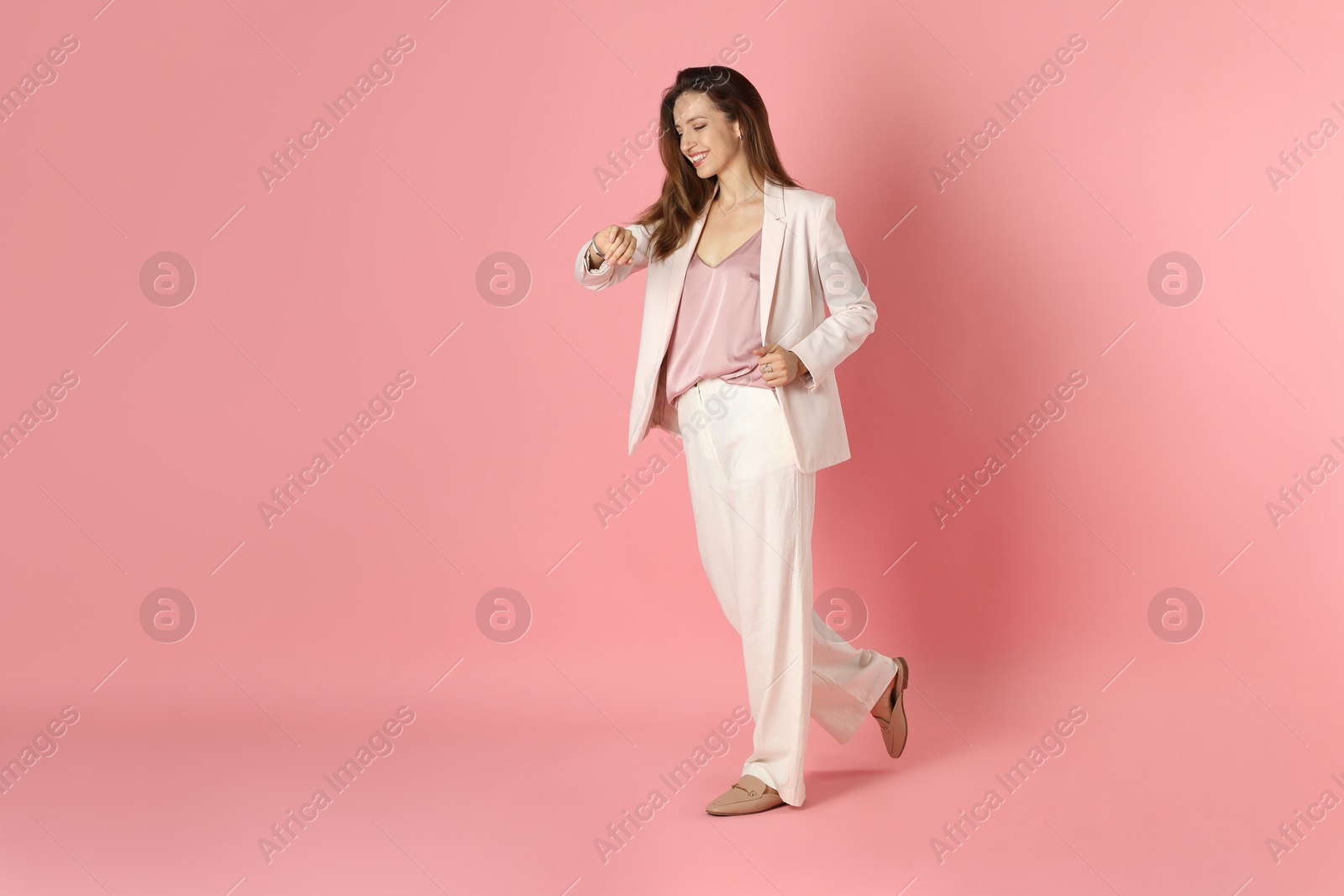 Photo of Beautiful woman in stylish white suit on pink background, space for text