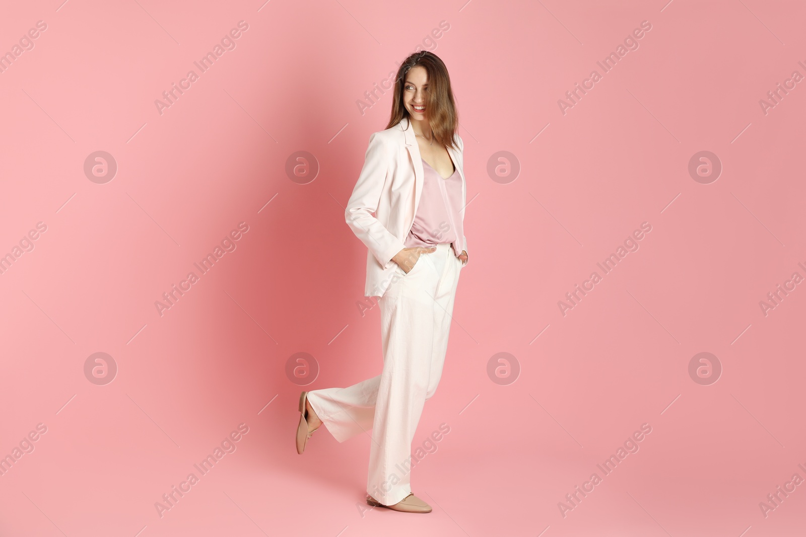 Photo of Beautiful woman in stylish white suit on pink background