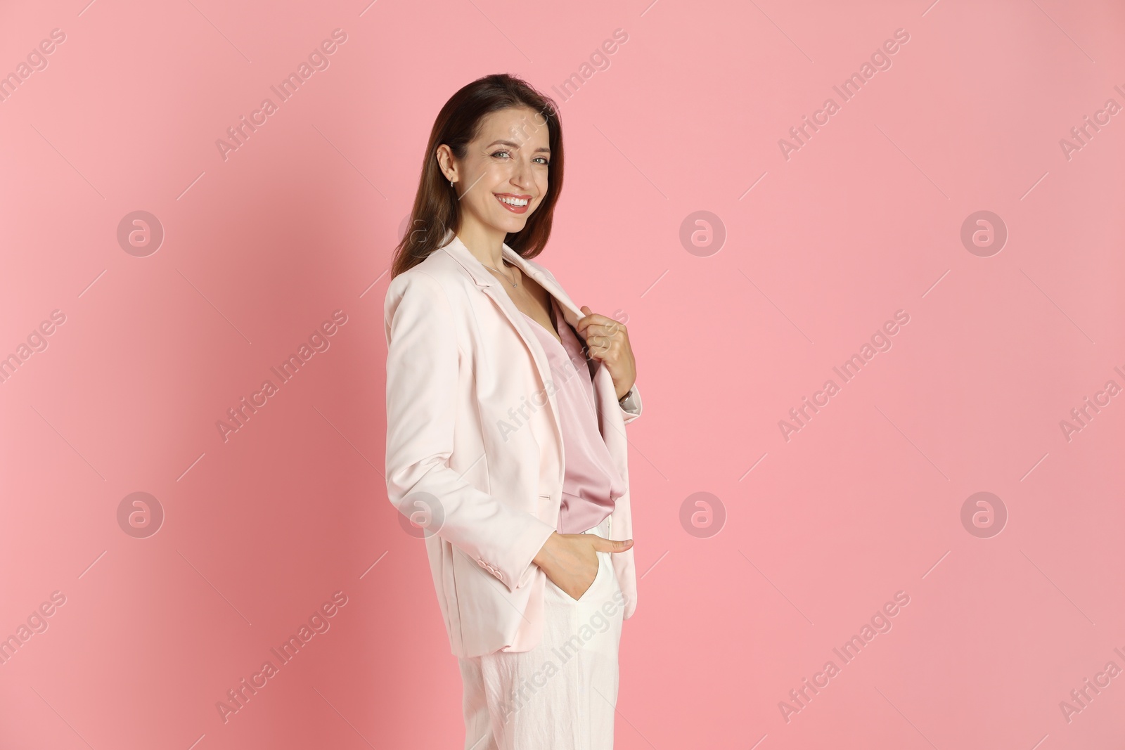 Photo of Beautiful woman in stylish white suit on pink background