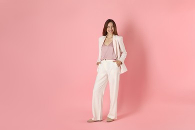 Beautiful woman in stylish white suit on pink background