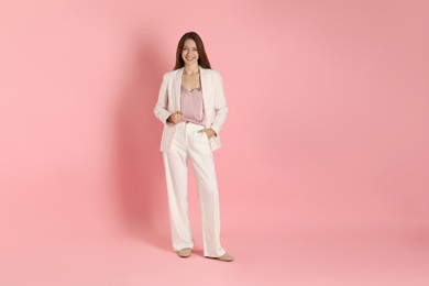 Beautiful woman in stylish white suit on pink background