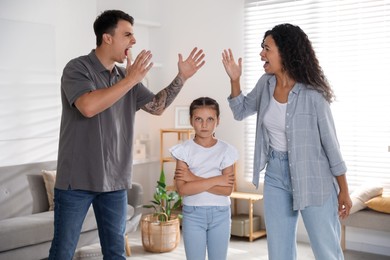 Divorce concept. Angry couple arguing and their sad daughter at home