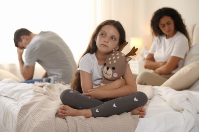 Divorce concept. Sad couple in bedroom, focus on their unhappy daughter