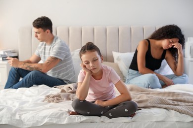 Divorce concept. Sad couple in bedroom, focus on their unhappy daughter