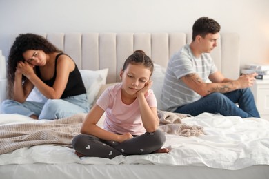 Divorce concept. Sad couple in bedroom, focus on their unhappy daughter