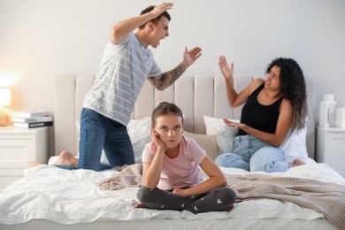 Photo of Divorce concept. Angry couple arguing in bedroom, focus on their sad daughter