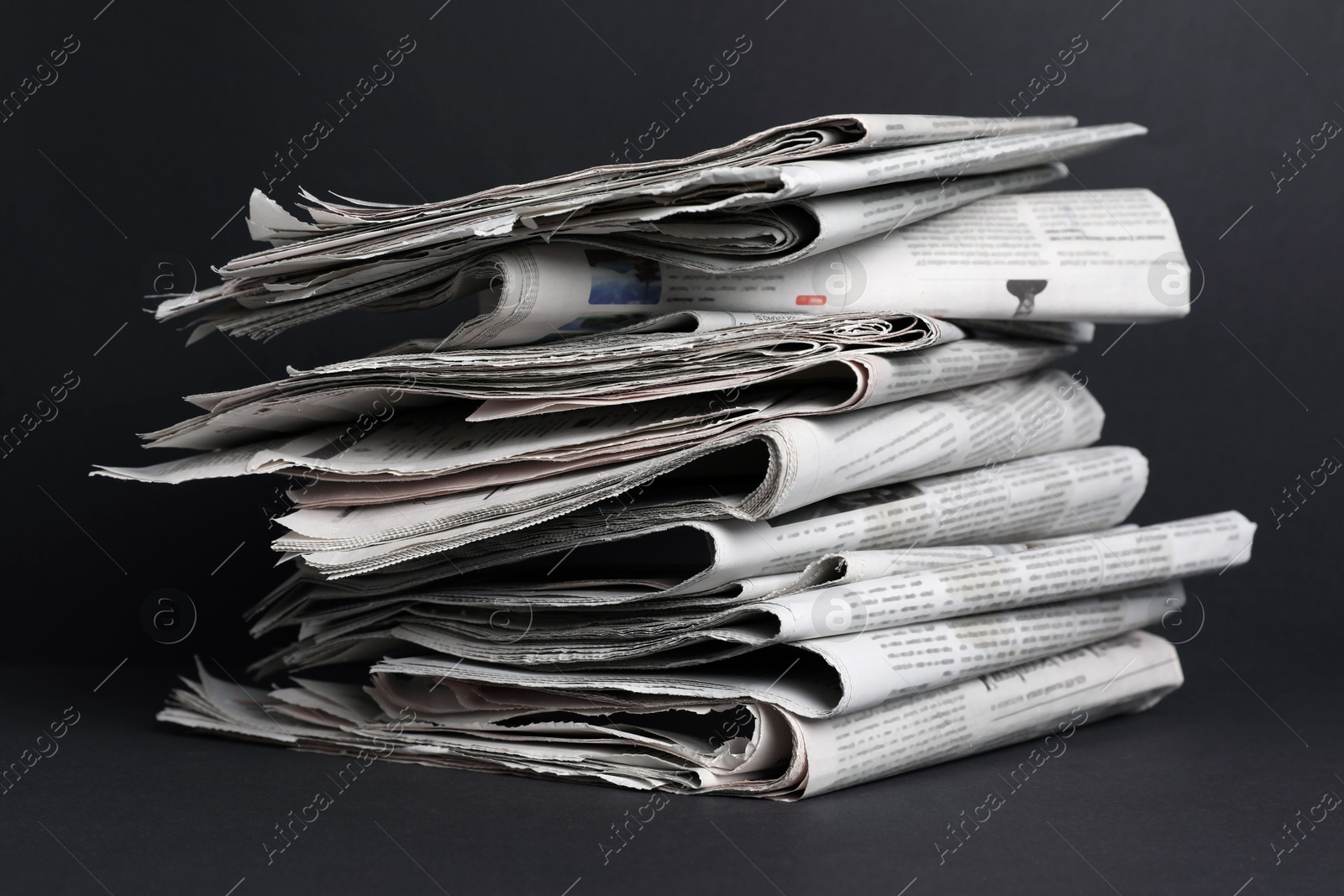 Photo of Stack of newspapers in different languages on black background, closeup