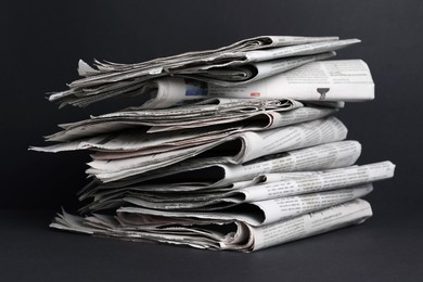 Photo of Stack of newspapers in different languages on black background, closeup