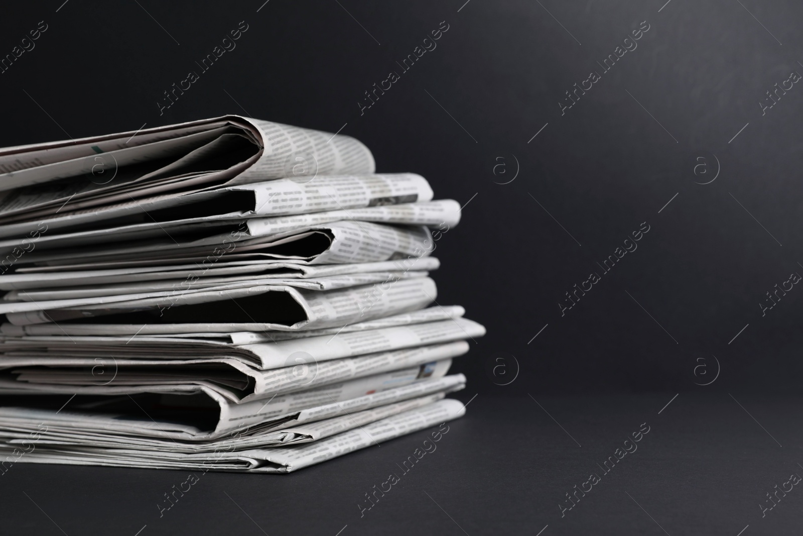 Photo of Stack of newspapers in different languages on black background. Space for text