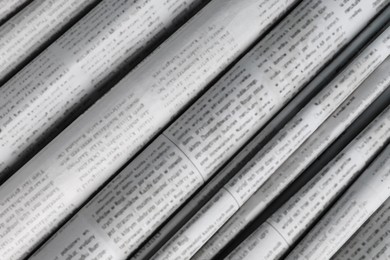 Photo of Many newspapers in different languages as background, closeup