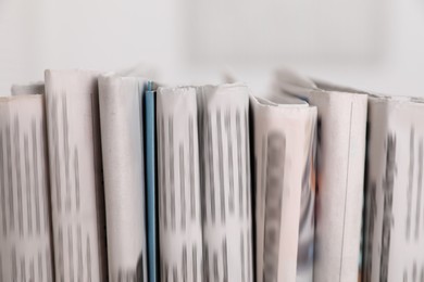 Photo of Many newspapers in different languages on blurred background, closeup