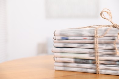 Stack of many newspapers in different languages on wooden table, space for text