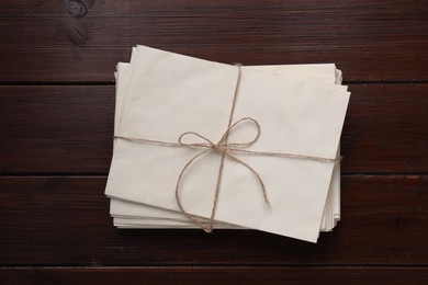 Stack of old letters tied with twine on wooden table, top view