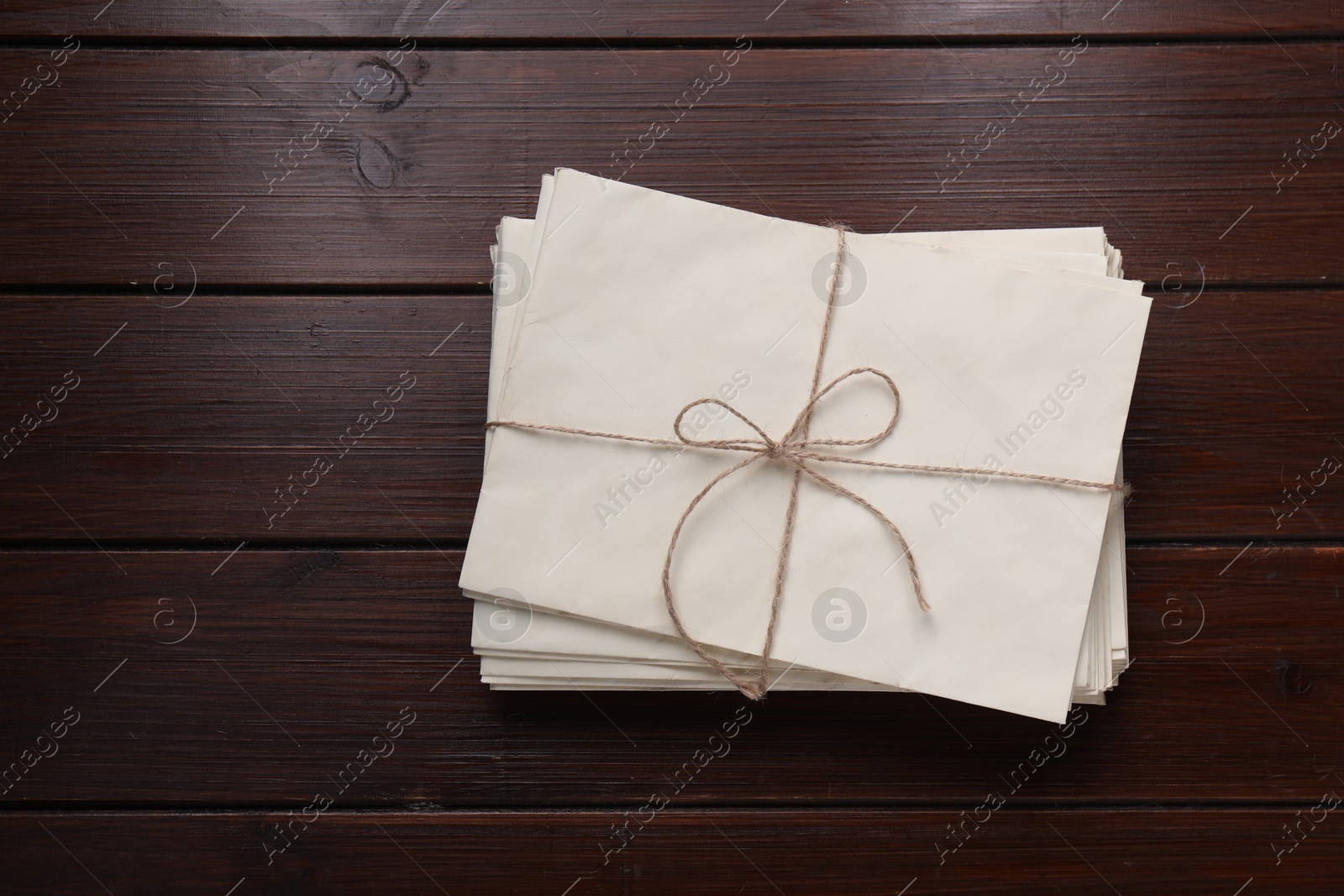 Photo of Stack of old letters tied with twine on wooden table, top view. Space for text