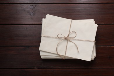 Stack of old letters tied with twine on wooden table, top view. Space for text