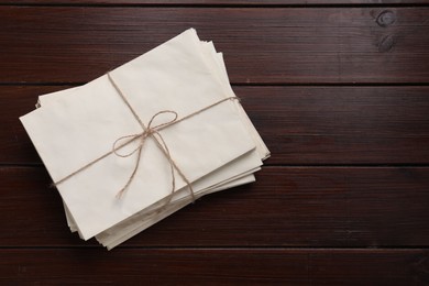 Photo of Stack of old letters tied with twine on wooden table, top view. Space for text