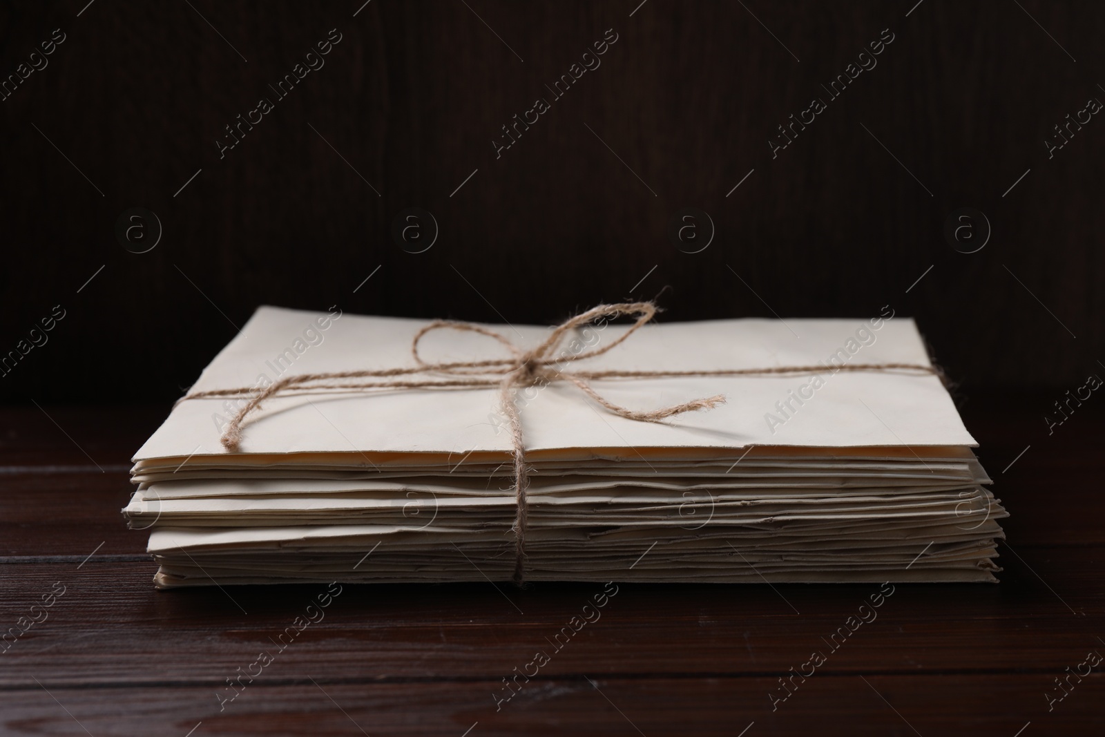 Photo of Stack of old letters tied with twine on wooden table, closeup