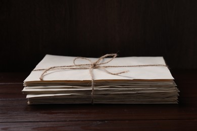 Photo of Stack of old letters tied with twine on wooden table, closeup