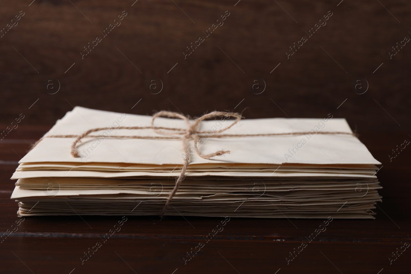 Photo of Stack of old letters tied with twine on wooden table, closeup