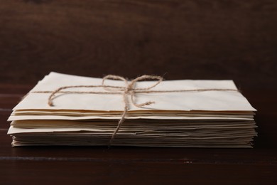 Photo of Stack of old letters tied with twine on wooden table, closeup