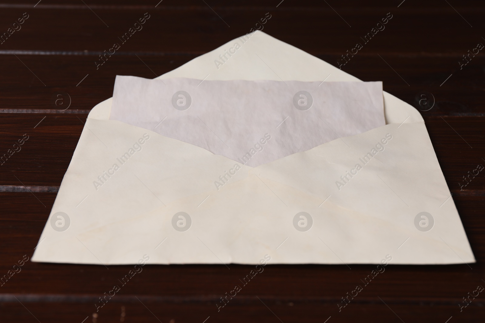 Photo of Envelope with old letter on wooden table, closeup