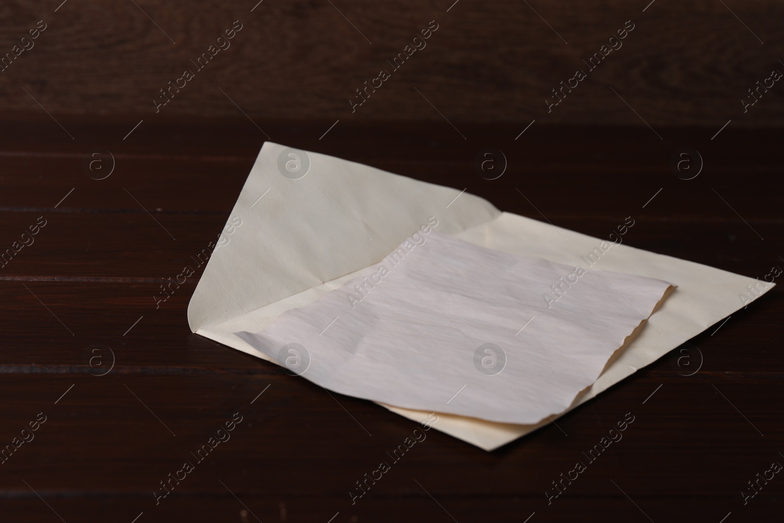 Photo of Envelope with old letter on wooden table, closeup