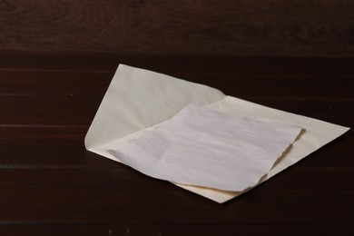 Envelope with old letter on wooden table, closeup