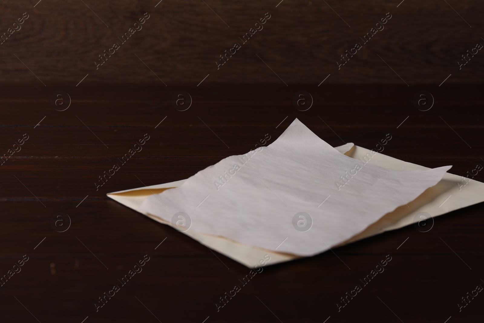 Photo of Old letter and envelope on wooden table, closeup