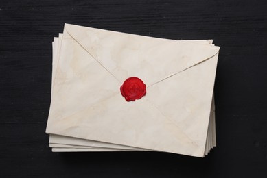 Photo of Stack of old letter envelopes on black wooden table, top view