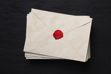 Photo of Stack of old letter envelopes on black wooden table, top view