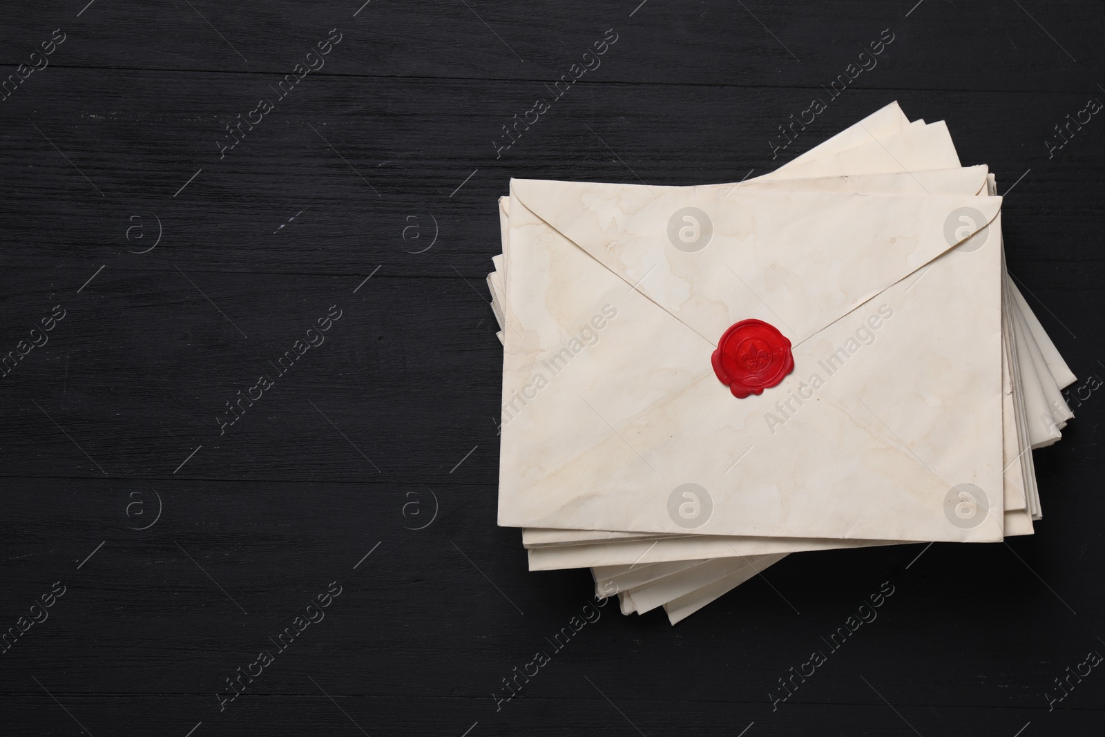 Photo of Stack of old letter envelopes on black wooden table, top view