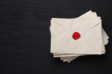 Photo of Stack of old letter envelopes on black wooden table, top view