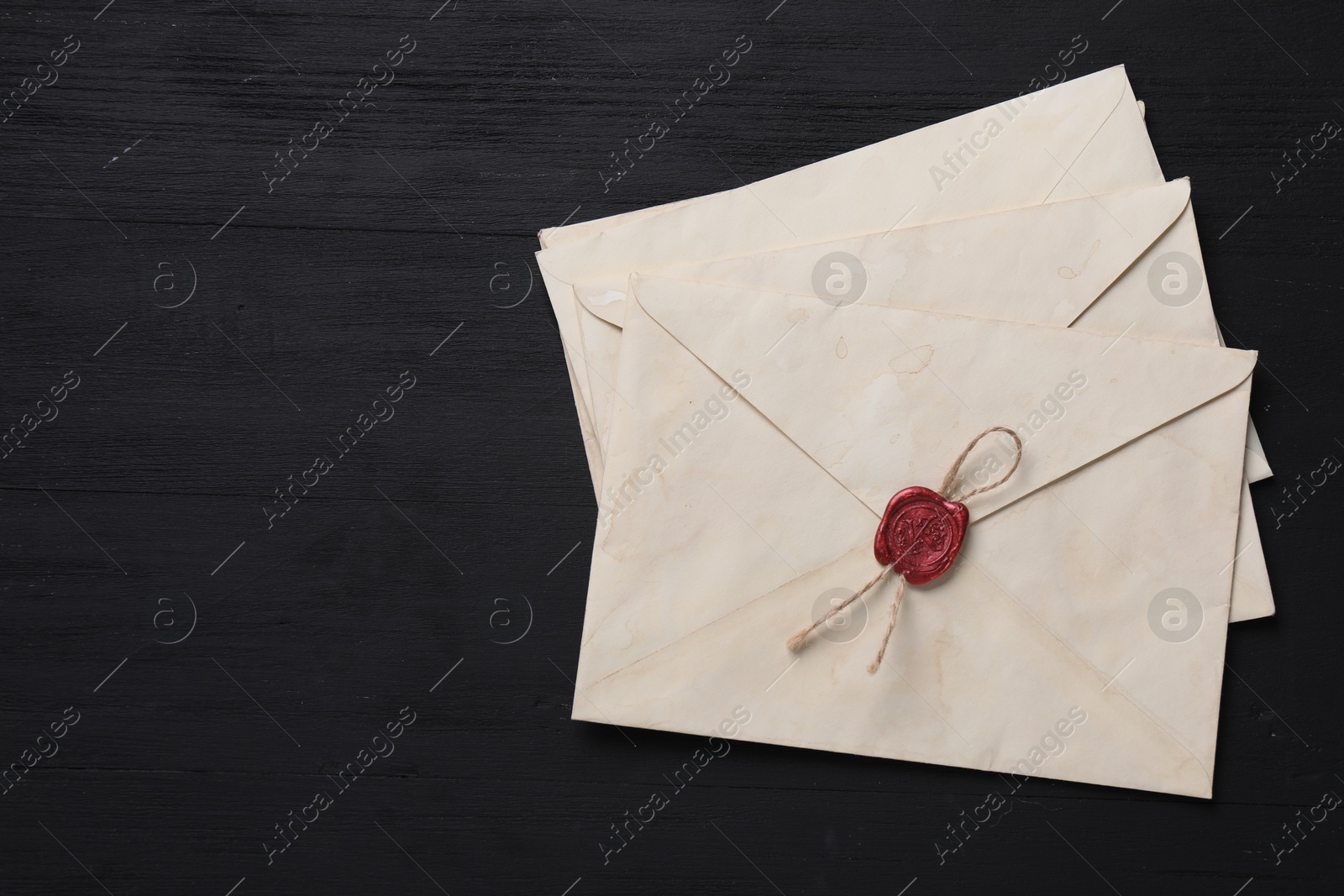 Photo of Old letter envelopes and fountain pen on black wooden table, top view