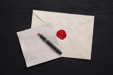 Old letter, envelope and fountain pen on black wooden table, top view